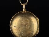 an old gold pocket watch with a chain on a black surface