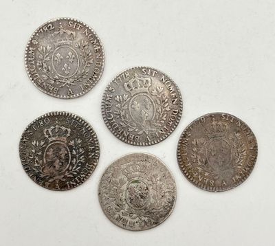 cinq pièces d'argent ornées d'une couronne, posées sur une surface blanche