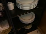 une étagère sur laquelle sont posées des assiettes et des tasses, dans une cuisine