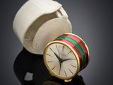 a small clock sitting next to a leather case