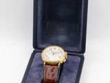a watch in a box with a brown leather strap