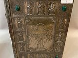 an old silver book with green buttons on it sitting on a white surface