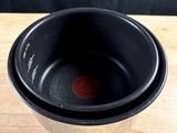 un bol noir posé sur une table en bois, sur fond noir