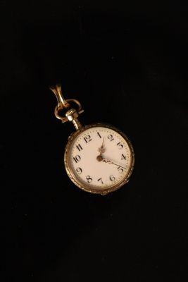 a close up of a pocket watch on a black surface