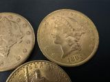 three gold coins sitting on top of each other on a black surface