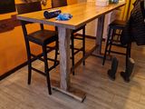 une table en bois avec des chaises et un tableau noir accroché au mur
