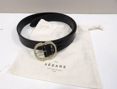 black leather belt with a gold buckle on a white table