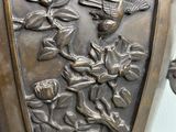 a bronze vase with a bird and flowers on it