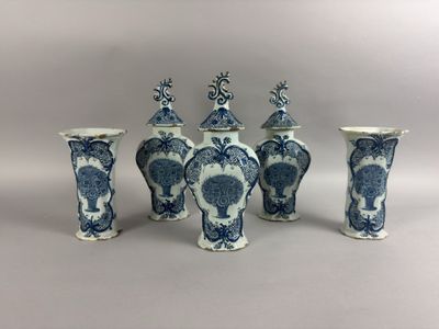 quatre vases bleus et blancs sont alignés sur un fond blanc
