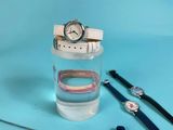 a glass of water with a watch and a pair of bracelets