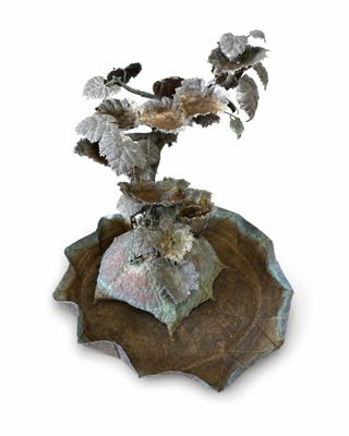 un vase en métal contenant une plante, posé sur une assiette