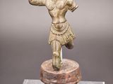 une figurine en bronze représentant un homme, posée sur un socle
