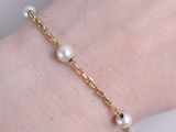 a close up of a person ' s hand wearing a gold bracelet with pearls