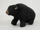 a small black bear that is standing on a white surface