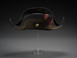 une photo d'un chapeau posé sur un support transparent, sur fond noir