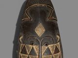 a close up of a wooden mask on a gray background
