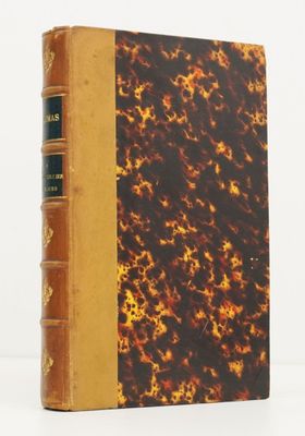 un vieux livre à la couverture marron posé sur une table blanche