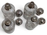 a group of glass jars with silver lids on a white surface