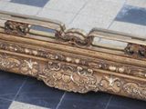 a mirror with a gold frame on a tiled floor