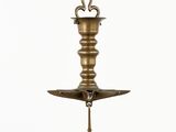 an antique brass candle holder hanging from a chain on a white background