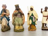 three figurines of people dressed in traditional clothing are posed in front of a white background