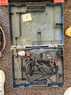 une boîte à outils contenant un marteau et d'autres outils, posée par terre