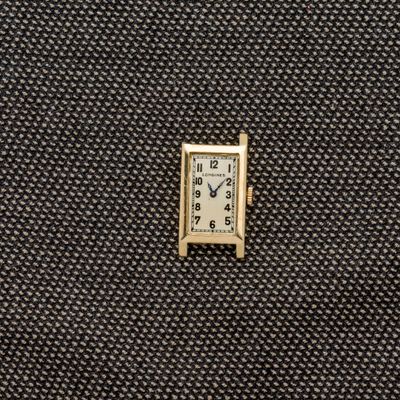 une petite horloge carrée posée sur un morceau de tissu
