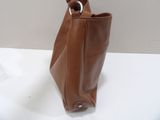 someone is holding a brown purse on a white table