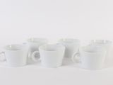 six white coffee cups are lined up on a white surface