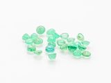 a close up of a bunch of green glass beads on a white surface