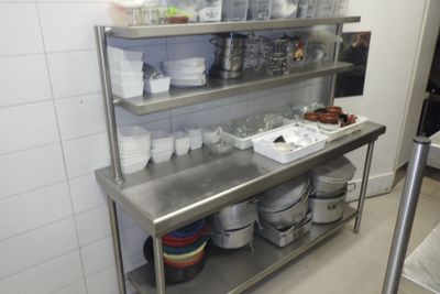 une étagère en acier inoxydable sur laquelle sont posés des plats, dans une cuisine