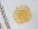 a gold sunflower brooch and a silver chain