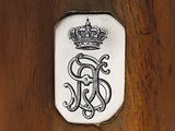 an antique silver plate with a crown on it on a wooden table