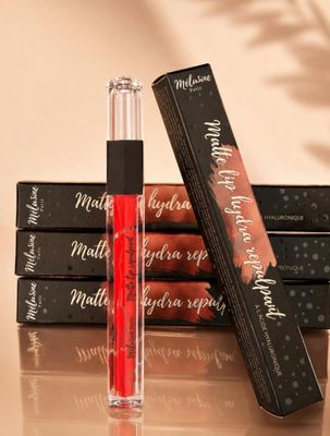 a close up of a bottle of lipstick next to a stack of boxes