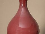 a red vase sitting on a table with a gold lid