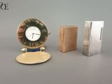 une horloge posée à côté d'un briquet et d'un livre