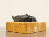 a statue of a turtle on a marble block on a table