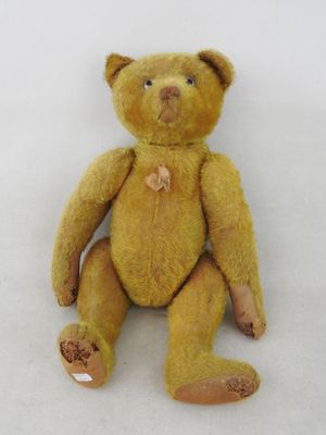 un petit ours en peluche jaune assis sur une surface blanche