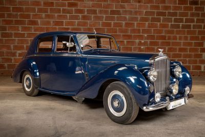 a blue car that is parked in front of a brick wall
