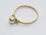 Gros plan sur une bague en or ornée d'une perle