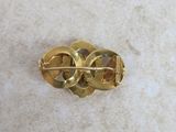 an image of a gold brooch on a white surface