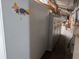 a white refrigerator in a room with pipes on the wall