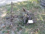 a rusty plow sitting in the grass next to a log