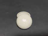 a small white vase sitting on a black surface