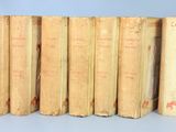 several old books are lined up in a row on a blue surface