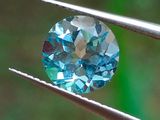 un gros plan d'un diamant bleu tenu par une pince