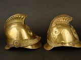 pair of antique brass roman helmet bookends on a black background