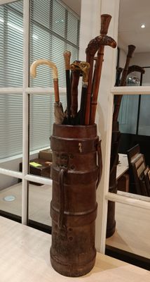 a vase with umbrellas and canes in it on a table