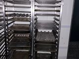 two racks with trays of food on them in a kitchen