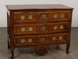 an antique chest of drawers with brass handles on a wooden floor